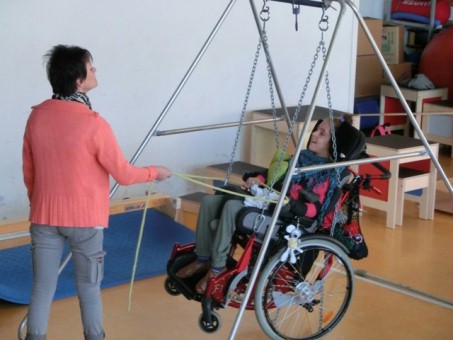 Auf dem Bild sieht man eine Schülerin, die ihn ihrem Rollstuhl strahlend schaukelt.