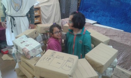 Zwei Schülerinnen stehen in einem aus Kartons gebauten Verlies und lachen.