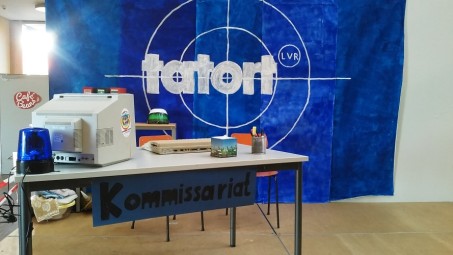 Bühnenbereich mit Schreibtisch und Tatort-Logo im Hintergrund