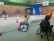 Foto: Vier Schüler*innen im Rollstuhl fahren in der Turnhalle um verschiedene Hindernisse herum.