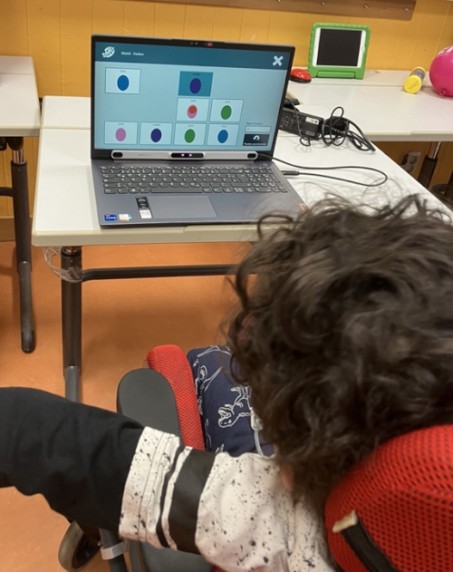 Foto: Junge von hinten, der einen Laptop mit einer Augensteuerung ansteuert.