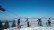 Foto: Schüler*innnen auf Skiern stehen vor Bergpanorama in der Schlange 