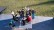 Gruppenfoto: Schüler*innen und Lehrer*innen in der Sonne mit Bechern und Kuchen auf und um eine Tischtennisplatte sitzend und stehend vor einer grünen Wiese.